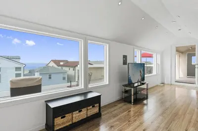 an empty living room with large windows and a table at Oceanview Corner Home W Rooftop Deck, One House From Beach By Beachview Rentals in Newport Beach