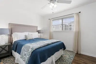 a white bedroom with a bed and a window at Oceanview Corner Home W Rooftop Deck, One House From Beach By Beachview Rentals in Newport Beach
