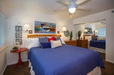 a bedroom with a blue bed and a ceiling fan at 6Br Duplex W Oceanview Patios, Steps To 40Th Street Beach By Beachview Rentals in Newport Beach