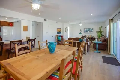 a dining room and living room with a wooden table at 6Br Duplex W Oceanview Patios, Steps To 40Th Street Beach By Beachview Rentals in Newport Beach