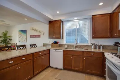 a large kitchen with wooden cabinets and a window at 6Br Duplex W Oceanview Patios, Steps To 40Th Street Beach By Beachview Rentals in Newport Beach