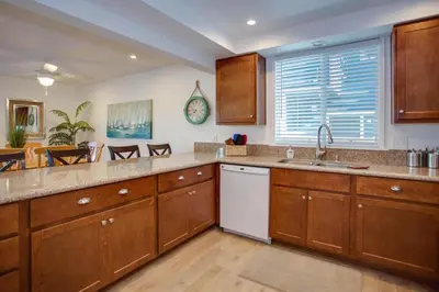 a large kitchen with wooden cabinets and a sink at Ultimate Coastal Retreat Seconds From Sand W Oceanviews By Beachview Rentals in Newport Beach
