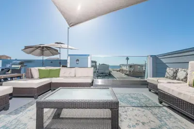 a patio with couches and a table and an umbrella at Modern 4Br Vacation Home W Ocean Views And Rooftop Deck By Beachview Rentals in Newport Beach
