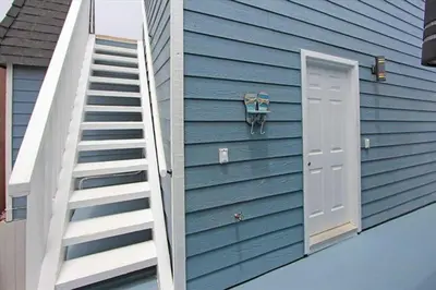 a blue house with a staircase and a door at Modern 4Br Vacation Home W Ocean Views And Rooftop Deck By Beachview Rentals in Newport Beach