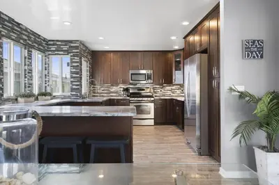 a kitchen with stainless steel appliances and wooden cabinets at Modern 4Br Vacation Home W Ocean Views And Rooftop Deck By Beachview Rentals in Newport Beach