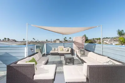 a patio with white furniture on a roof at Modern 4Br Vacation Home W Ocean Views And Rooftop Deck By Beachview Rentals in Newport Beach