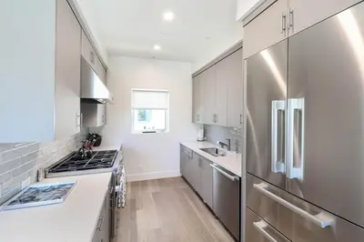 a kitchen with white cabinets and a stainless steel refrigerator at Luxury Stay Corona del Mar, Short Walk to Beach in Newport Beach