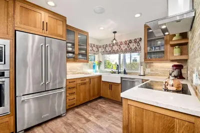 a kitchen with wooden cabinets and a stainless steel refrigerator at Fresh & Modern 3BR - Just Blocks from Beach in Encinitas