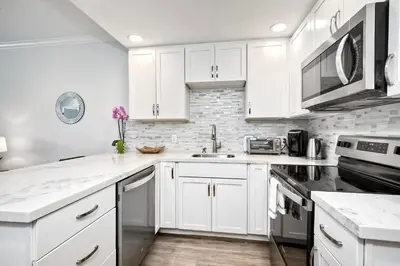 a white kitchen with white cabinets and appliances at La Costa Gem - Condo for 3 in Carlsbad