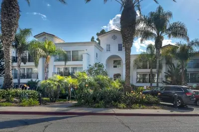a car parked in front of a building with palm trees at La Costa Gem - Condo for 3 in Carlsbad