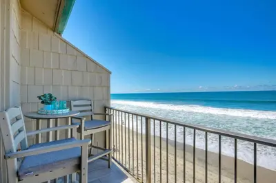 a balcony with two chairs and the beach at Seaside Sunset in Carlsbad