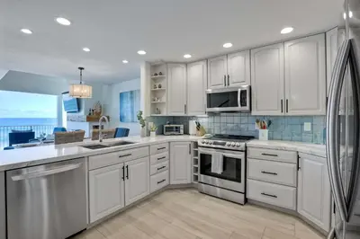 a kitchen with white cabinets and a large window at Seaside Sunset in Carlsbad