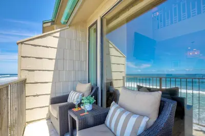 a balcony with two wicker chairs and a table at Seaside Sunset in Carlsbad