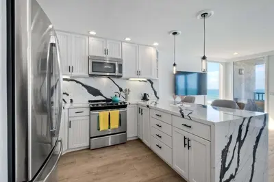 a kitchen with white cabinets and a stainless steel refrigerator at Solana Sunset - Stunning Beachside Retreat for 4 in Solana Beach