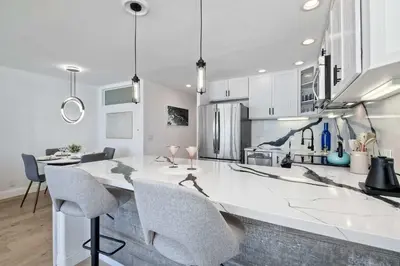 a kitchen with a large white counter and chairs at Solana Sunset - Stunning Beachside Retreat for 4 in Solana Beach