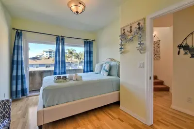 a bedroom with a bed with blue curtains and a window at South Pacific - Walk to Beach in Oceanside