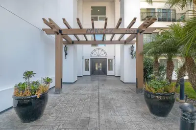 a entrance to a white building with a wooden pergola at Southern Exposure with Private Balcony in Carlsbad