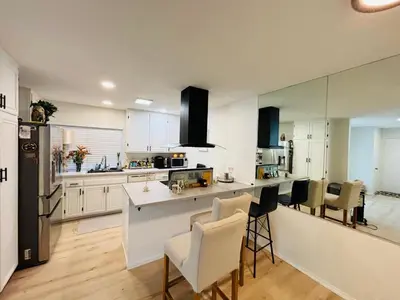 a kitchen with white cabinets and a counter with chairs at Amazing House in La Jolla, CA in San Diego