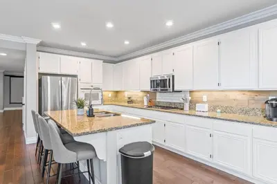 a kitchen with white cabinets and a island with bar stools at King Bed Temecula Getaway Amazing Pool and Theatre in Murrieta