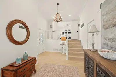 a living room with a mirror and a wooden dresser at Shores Luxury! Private Hot Tub, Fire Pit, Steps to Beach & Village Life in San Diego