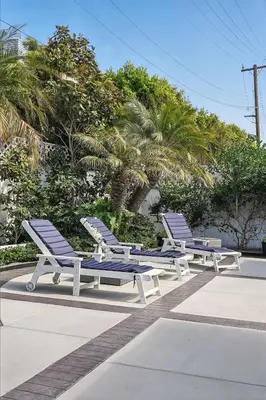 three blue and white lounge chairs next to palm trees at Shores Luxury! Private Hot Tub, Fire Pit, Steps to Beach & Village Life in San Diego