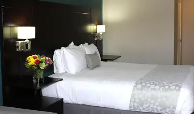 a bedroom with a large white bed with flowers on a table at Best Western PLUS La Mesa San Diego in La Mesa
