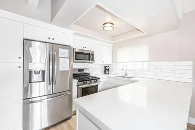 a kitchen with white cabinets and a stainless steel refrigerator at Pet-Friendly 3Br W Oceanview Balcony, Only Steps To Sand By Beachview Rentals in Newport Beach