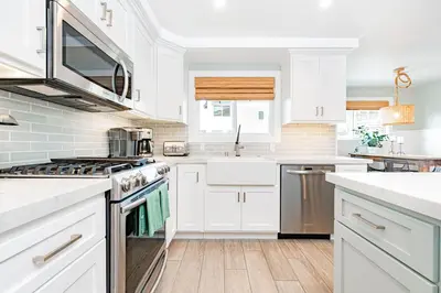 a kitchen with white cabinets and stainless steel appliances at Luxury 1Br Retreat W High-End Interior - Steps From Beach By Beachview Rentals in Newport Beach