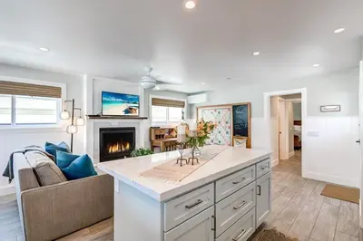 a living room with a kitchen with a fireplace at Luxury 1Br Retreat W High-End Interior - Steps From Beach By Beachview Rentals in Newport Beach