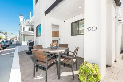 a wooden table and chairs on a patio at Luxury 1Br Retreat W High-End Interior - Steps From Beach By Beachview Rentals in Newport Beach