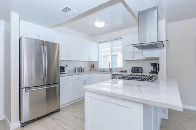 a kitchen with white cabinets and a stainless steel refrigerator at Spacious 3Br W Oceanview Patio, Steps To 35Th St Beach By Beachview Rentals in Newport Beach