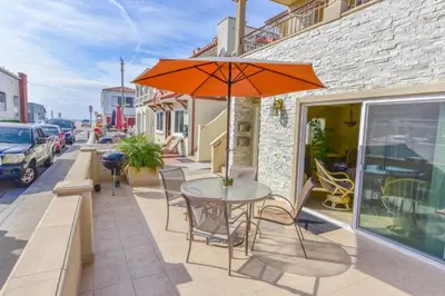 a table and chairs with an umbrella on a sidewalk at Spacious 3Br W Oceanview Patio, Steps To 35Th St Beach By Beachview Rentals in Newport Beach