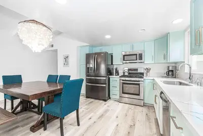 a kitchen with a wooden table and blue cabinets at Remodeled 4Br Duplex, Steps From Beach And Boardwalk By Beachview Rentals in Newport Beach