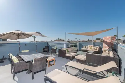 a deck with chairs and tables and an umbrella at 6Br Oceanview Home W Rooftop Deck, Steps To 40Th St Beach By Beachview Rentals in Newport Beach