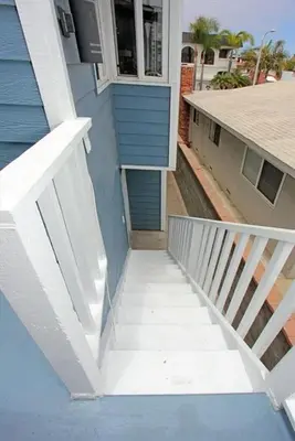 a stairway leading up to a blue building at 6Br Oceanview Home W Rooftop Deck, Steps To 40Th St Beach By Beachview Rentals in Newport Beach