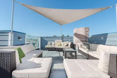 a patio with white couches and chairs on a roof at 6Br Oceanview Home W Rooftop Deck, Steps To 40Th St Beach By Beachview Rentals in Newport Beach