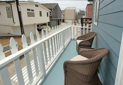 two chairs sitting on a porch with a white fence at Cozy 2Br W Ac And Private Patio, Steps To 40Th St Beach By Beachview Rentals in Newport Beach
