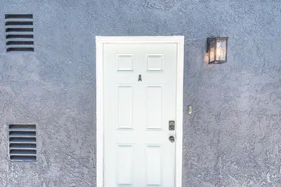 a white door on a gray wall with a light at Renovated 3Br W Stylish Interior Steps From 29Th St Beach By Beachview Rentals in Newport Beach