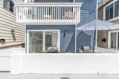 a balcony with a table and an umbrella on a house at Renovated 3Br W Stylish Interior Steps From 29Th St Beach By Beachview Rentals in Newport Beach