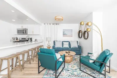 a living room with blue chairs and a table at Renovated 3Br W Stylish Interior Steps From 29Th St Beach By Beachview Rentals in Newport Beach