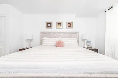 a white bedroom with a large white bed with two lamps at Renovated 3Br W Stylish Interior Steps From 29Th St Beach By Beachview Rentals in Newport Beach