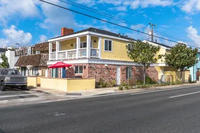 a brick house with a balcony on a street at Updated 2Br W Ac, Huge Patio, And Grill, One Block To Sand By Beachview Rentals in Newport Beach