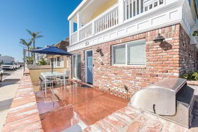 a brick house with a table and an umbrella at Updated 2Br W Ac, Huge Patio, And Grill, One Block To Sand By Beachview Rentals in Newport Beach