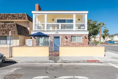 a brick house with an umbrella on a street at Updated 2Br W Ac, Huge Patio, And Grill, One Block To Sand By Beachview Rentals in Newport Beach