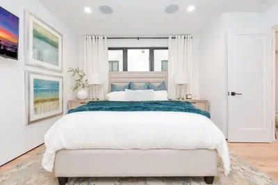 a white bedroom with a large bed and a window at High-End Balboa Peninsula Home W Ac And Ocean Views By Beachview Rentals in Newport Beach