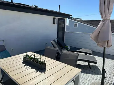 a patio with a wooden table and chairs and an umbrella at High-End Balboa Peninsula Home W Ac And Ocean Views By Beachview Rentals in Newport Beach
