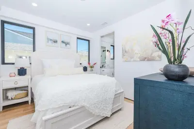 a white bedroom with a bed and a vase of flowers at High-End Balboa Peninsula Home W Ac And Ocean Views By Beachview Rentals in Newport Beach