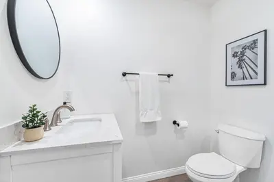 a white bathroom with a toilet and a mirror at Modern 2Br W Oceanview Patio, Half Block To 29Th St Beach By Beachview Rentals in Newport Beach