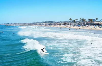 a person riding a wave on a surfboard in the ocean at Modern 2Br W Oceanview Patio, Half Block To 29Th St Beach By Beachview Rentals in Newport Beach