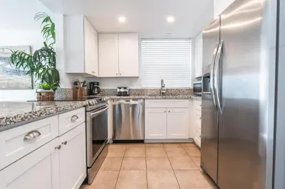 a kitchen with white cabinets and a stainless steel refrigerator at Pet-Friendly 3Br W Ac, Oceanview Patio, Steps From Beach By Beachview Rentals in Newport Beach